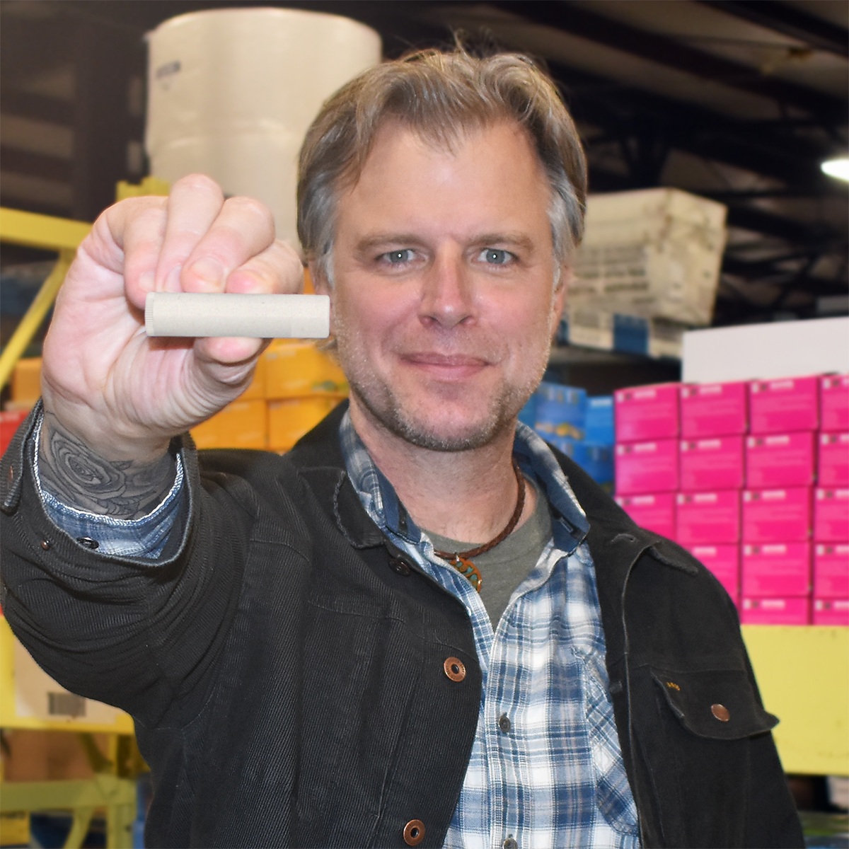 Eco Lips Founder Steve Shriver holds a tube of lip balm towards the camera.